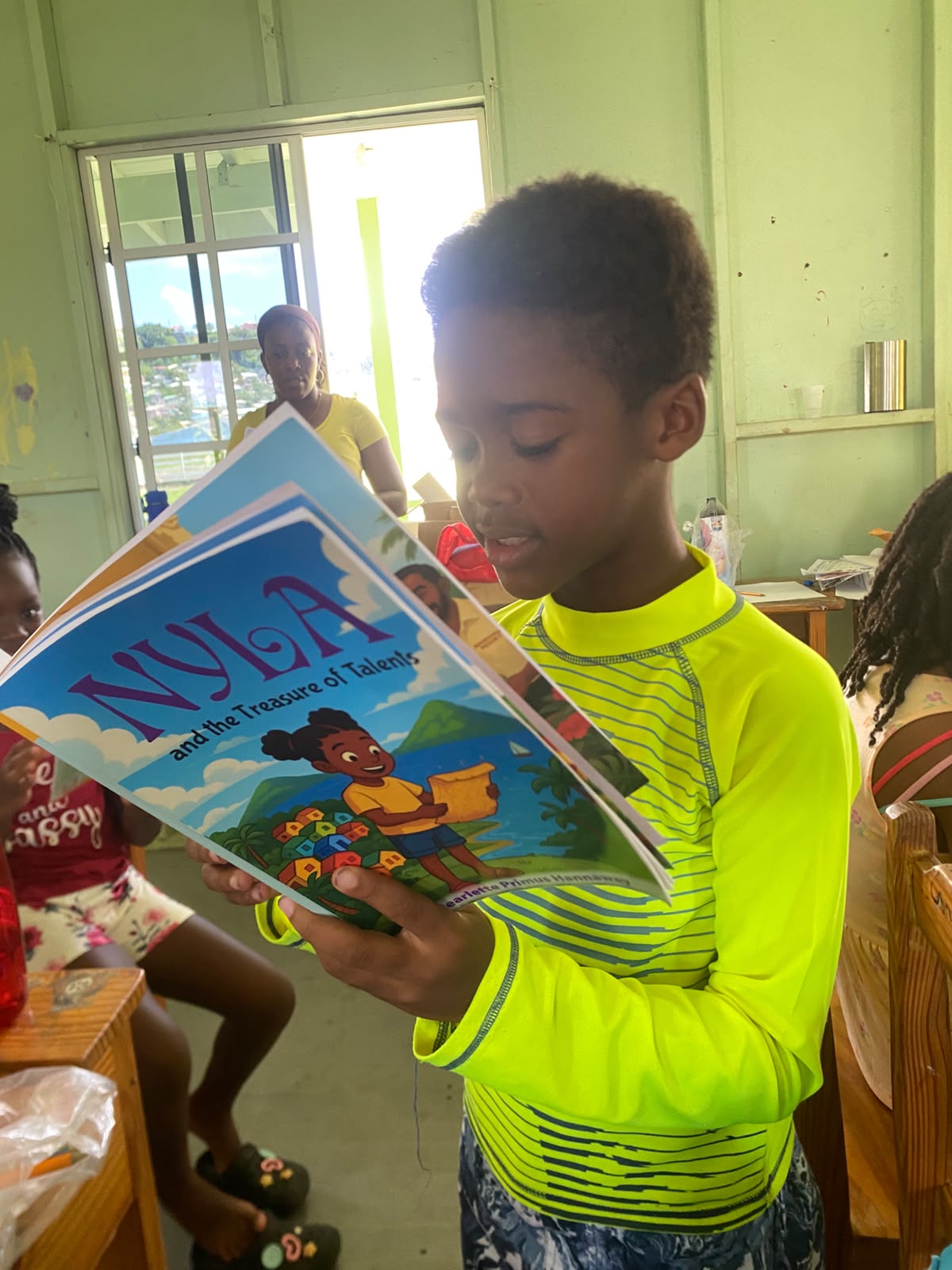 A boy in a bright yellow shirt reading Nyla and the Treasure of Talents