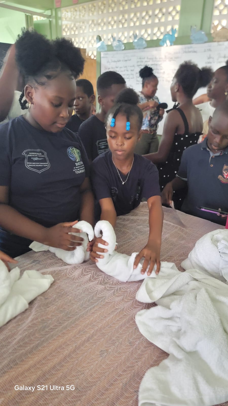 Students in a hospitality workshop learning towel-folding techniques